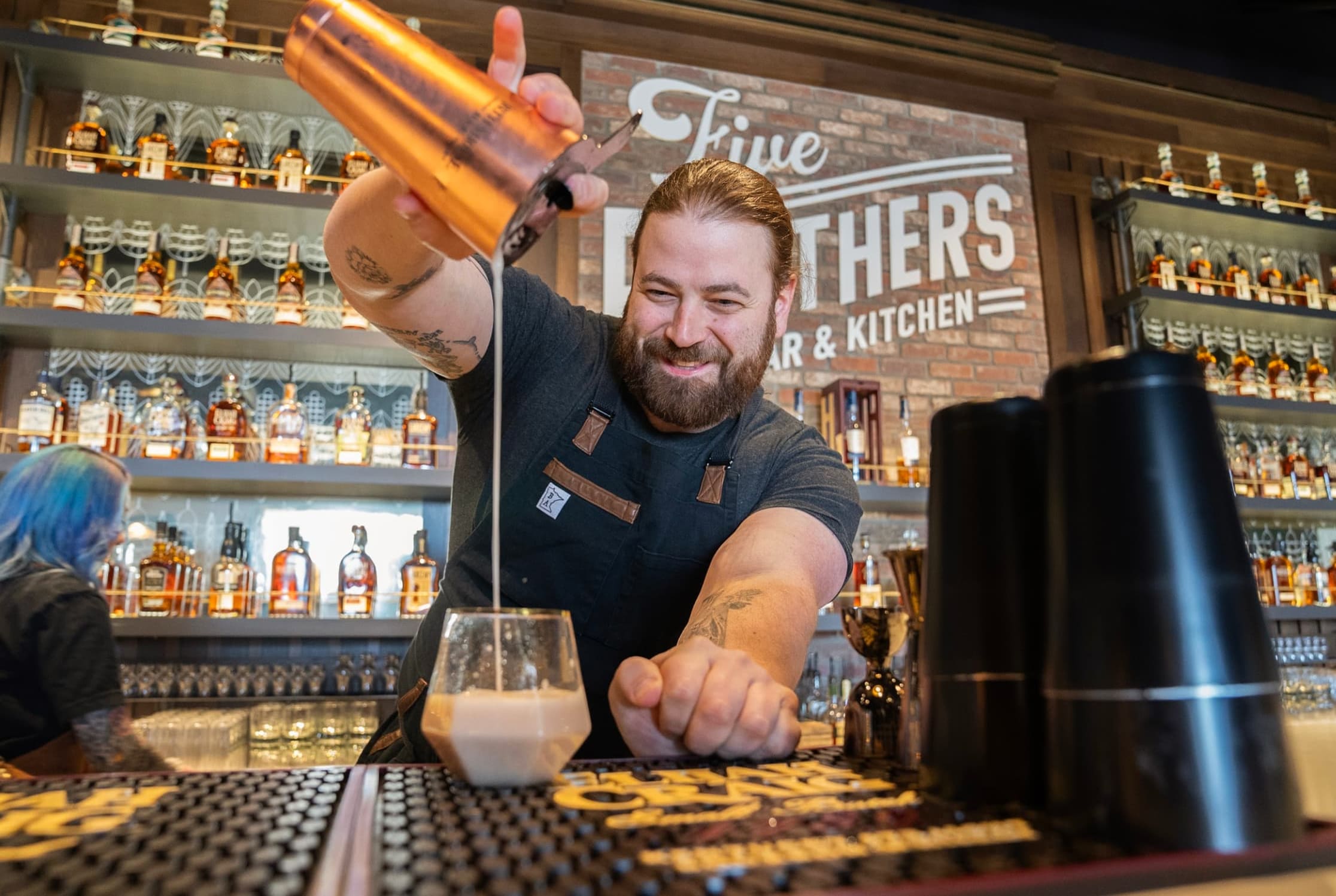 Bartender pouring a shaken drink into a glass