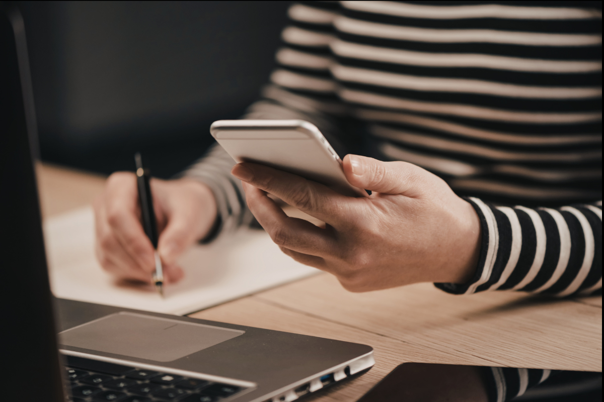 Woman working on phone and laptop