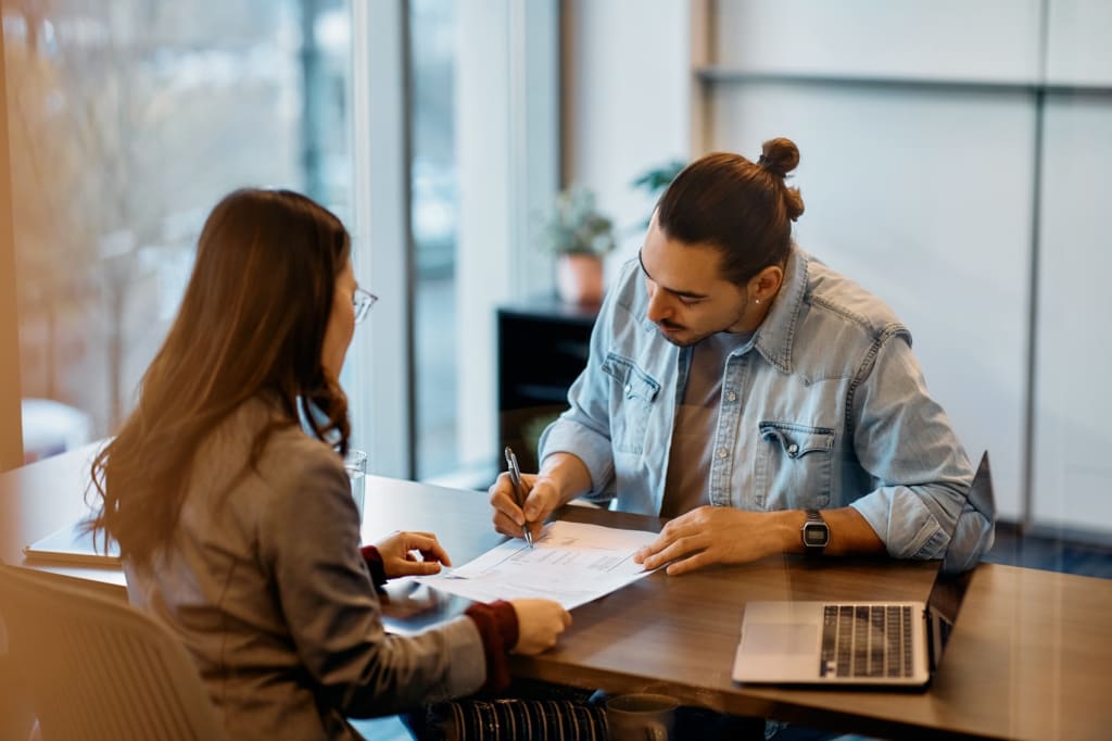 donna e uomo alla scrivania con fogli e computer