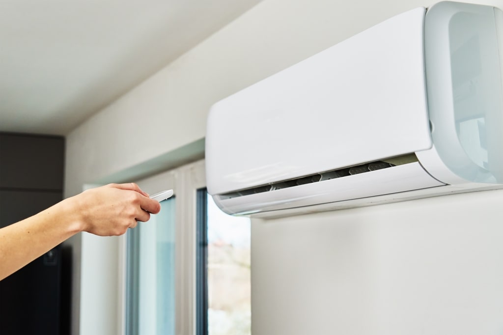 Persona che regola la temperatura del condizionatore con il telecomando Persona che regola la temperatura del condizionatore con il telecomando