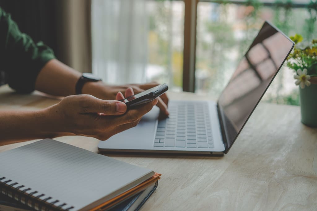 Persona che utilizza pc e smartphone contemporaneamente