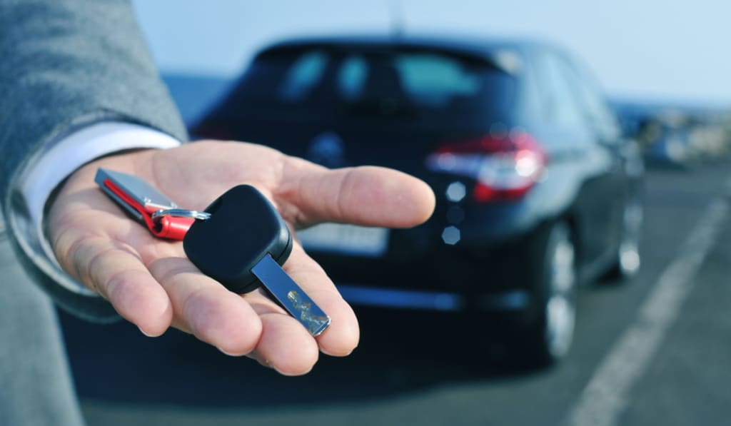 uomo che offre la chiave di un'auto a noleggio