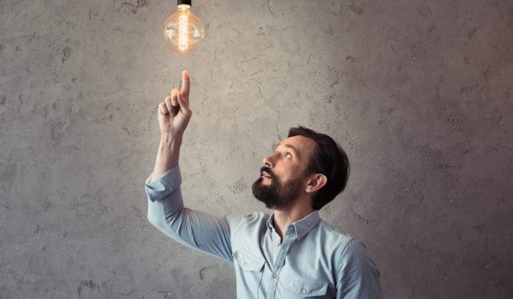uomo che punta alla lampadina illuminata uomo che punta alla lampadina illuminata