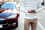 Persona accanto a un'auto che utilizza lo smartphone