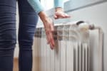 Donna che controlla la temperatura di un calorifero con le mani