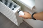 Persona che regola il termosifone attraverso la manopola