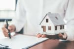 Agente immobiliare che tiene in mano il modellino di una casa