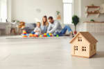 casa-in-miniatura-in-legno-con-famiglia-che-gioca-sullo-sfondo