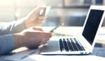 persona con carta di credito in mano utilizza pc e smartphone