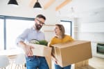 Coppia con scatoloni che sorride e trasloca nella casa nuova