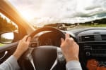 Dettaglio mani di uomo sul volante mentre guida in autostrada
