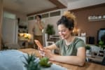 Donna a casa felice con smartphone