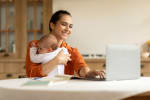 Donna a pc con bambino in braccio Donna a pc con bambino in braccio
