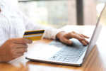 Donna al computer che tiene in mano la carta di credito