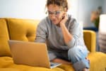 Donna con computer su divano giallo