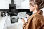 donna controlla elettrodomestici da tablet