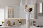 Donna sistema lampade in cucina