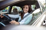 Donna sorridente al volante di un'auto