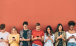 Ragazzi con smartphone vicino a muro rosso