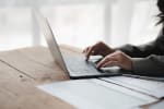 Mani di donna che scrivono al computer con documenti