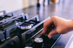 Mano che accende fornello del gas in cucina
