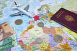 mappa del mondo centrata nell'Africa occidentale con sopra alcune banconote e monete marocchine un passaporto ed un aereo giocattolo
