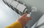 Persona che accende riscaldamento domestico e regola termosifone