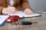 persona firma assicurazione auto con modellino e chiavi