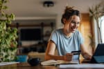 Ragazza al pc che sorride con carta di credito
