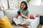 Ragazza che usa il cellulare seduta sul divano