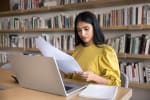 ragazza analizza fogli con computer davanti