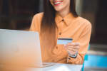 Ragazza che tiene in mano carta di credito mentre usa il computer
