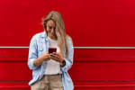 Ragazza con smartphone con sfondo rosso