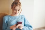 ragazza guarda il cellulare a casa