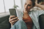 Ragazza seduta sul divano che usa il cellulare