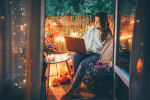 ragazza su balcone con luci accese e laptop