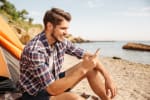 Ragazzo in spiaggia che usa smartphone
