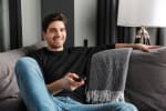 Ragazzo su divano con telecomando della televisione