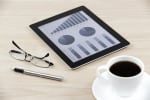 tablet con grafico finanziario caffè penna e occhiali