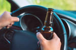 uomo al volante con birra in mano