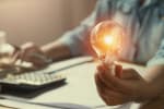 Uomo calcola offerte energia convenienti tenendo in mano una lampadina