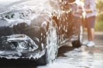 Uomo che lava l'auto sulla strada