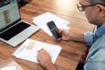 uomo fa calcoli con pc fogli e telefono