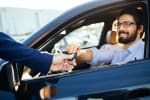uomo prende in consegna le chiavi dell'auto a noleggio