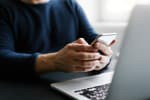 Uomo che usa smartphone davanti al computer