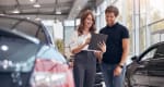 Venditrice presenta le caratteristiche dell'auto al cliente in showroom