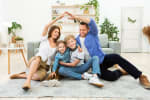 famiglia sorridente che simula forma di una casa