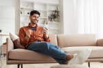 ragazzo sorridente con smartphone sul divano
