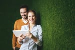coppia appoggiata a parete verde con tablet in mano