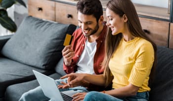 coppia felice al pc con carta di credito in mano